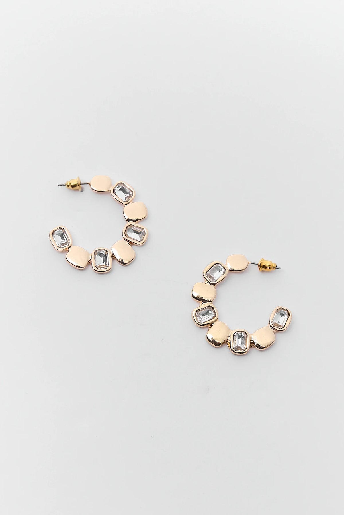Gold and rose gold hoop earrings with geometric designs on a light gray background