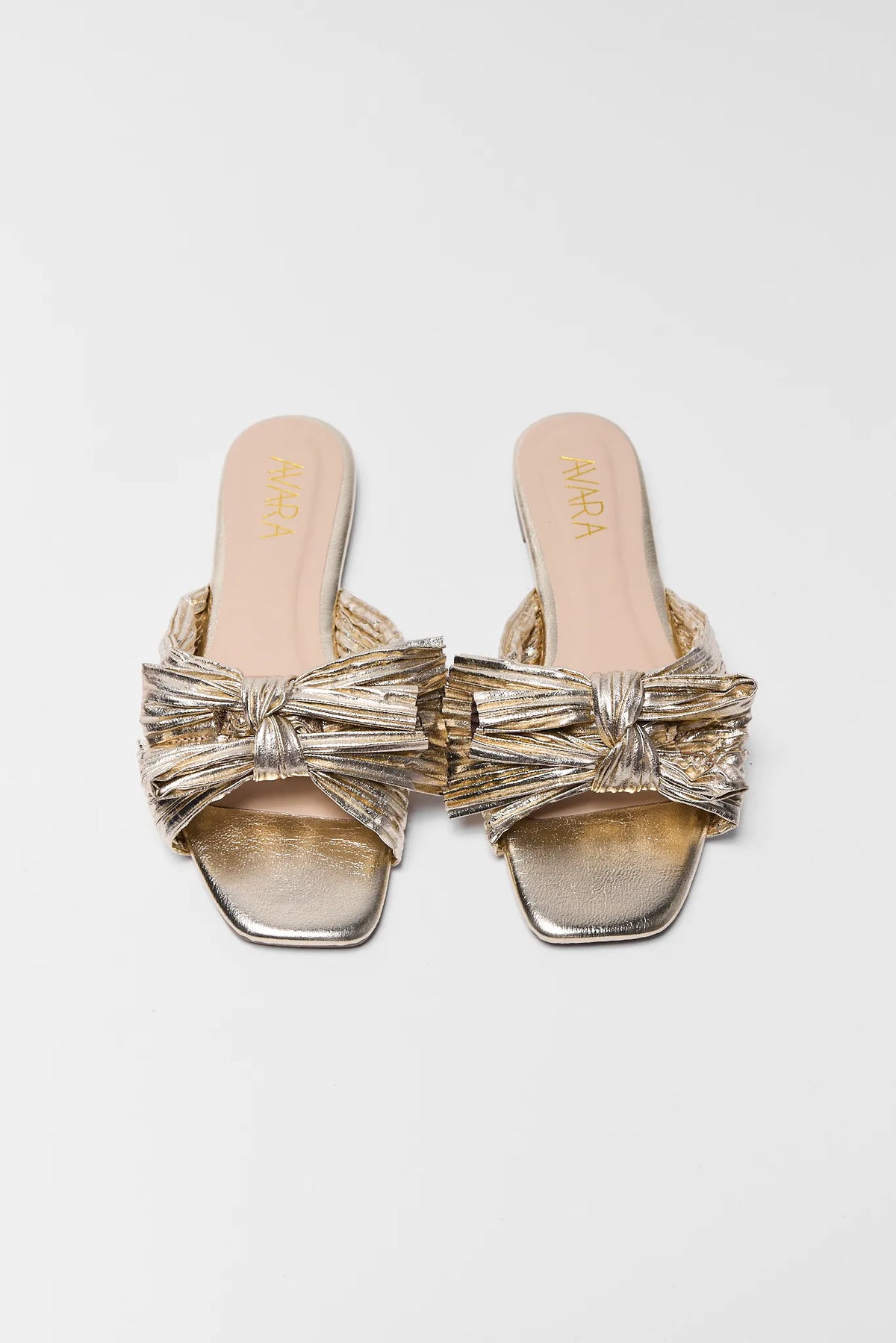 Gold sandals with bows on a light gray background