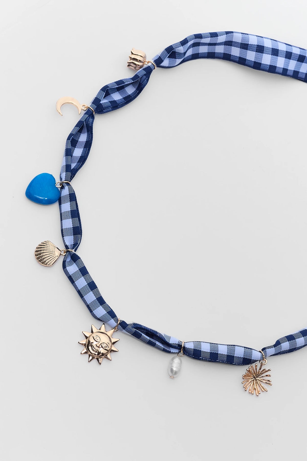 Blue gingham scarf necklace close-up with blue heart, gold shell, sun, moon, and pearl charms | Avara