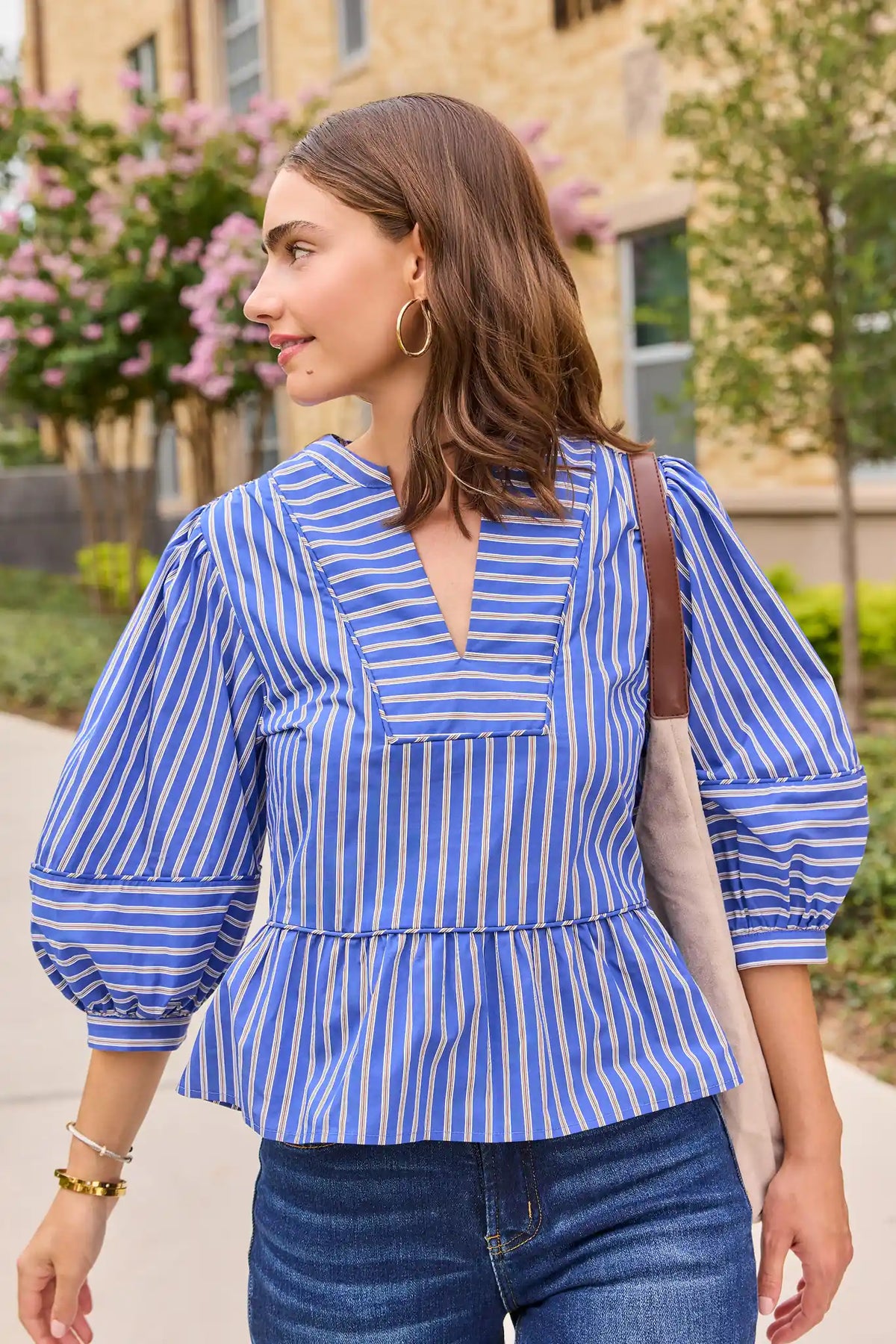 Blue striped split neck peplum top styled outdoors with jeans and a shoulder bag, lifestyle look | Avara