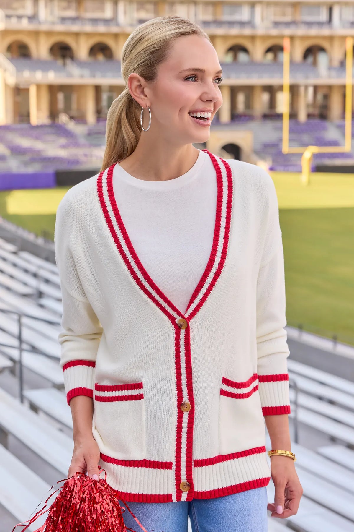 Jenna Ivory Applique Cardigan front view with red contrast trim, styled with jeans at stadium | Avara