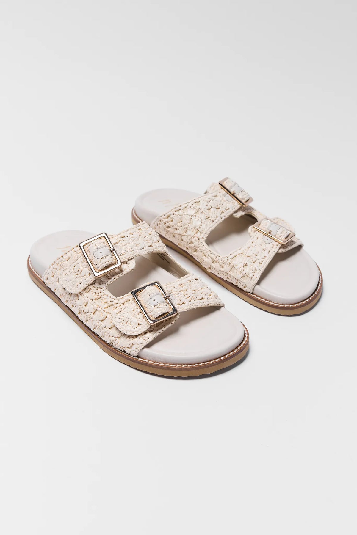 Tan woven raffia sandals with double gold buckles, angled side pair view | Avara