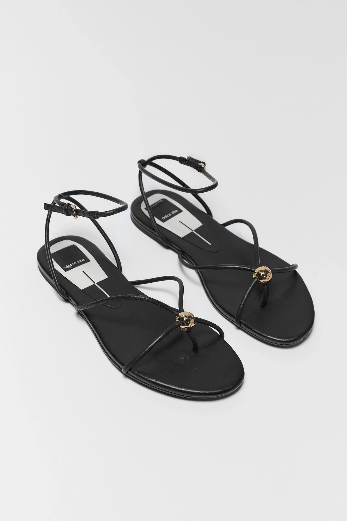 Two black leather Kenley sandals by Dolce Vita with thin straps and gold detail - Pair View | Avara