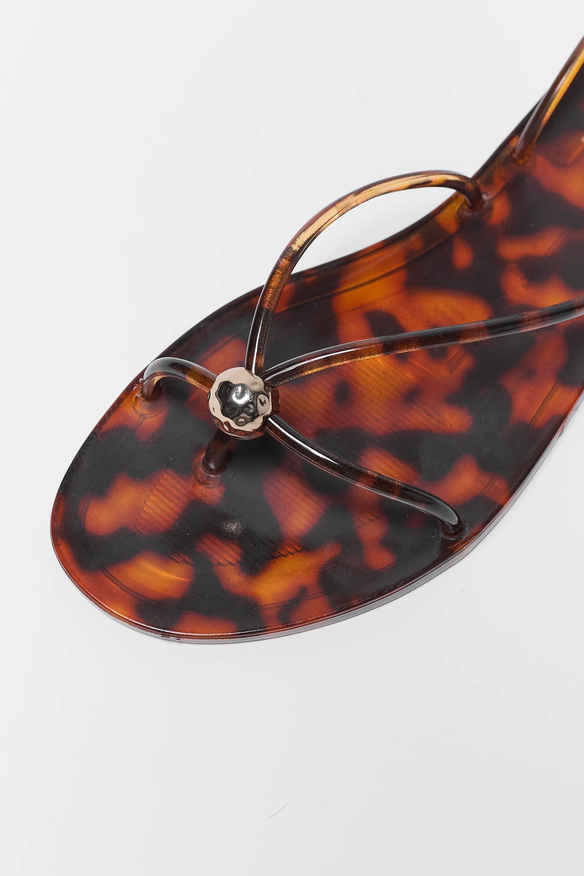 Tortoiseshell jelly sandal close-up showing gold flower toe detail - Close-Up | Avara