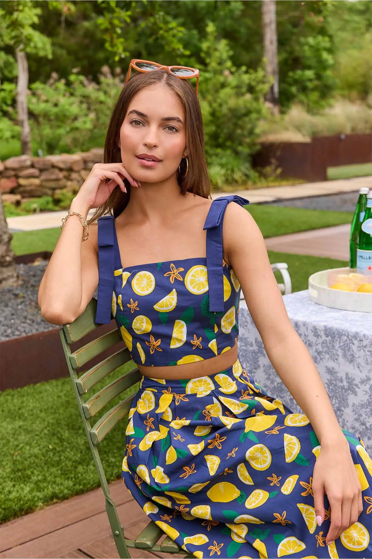 Navy lemon print cropped tank top with tie straps, model seated outdoors - Close-Up On Model | Avara