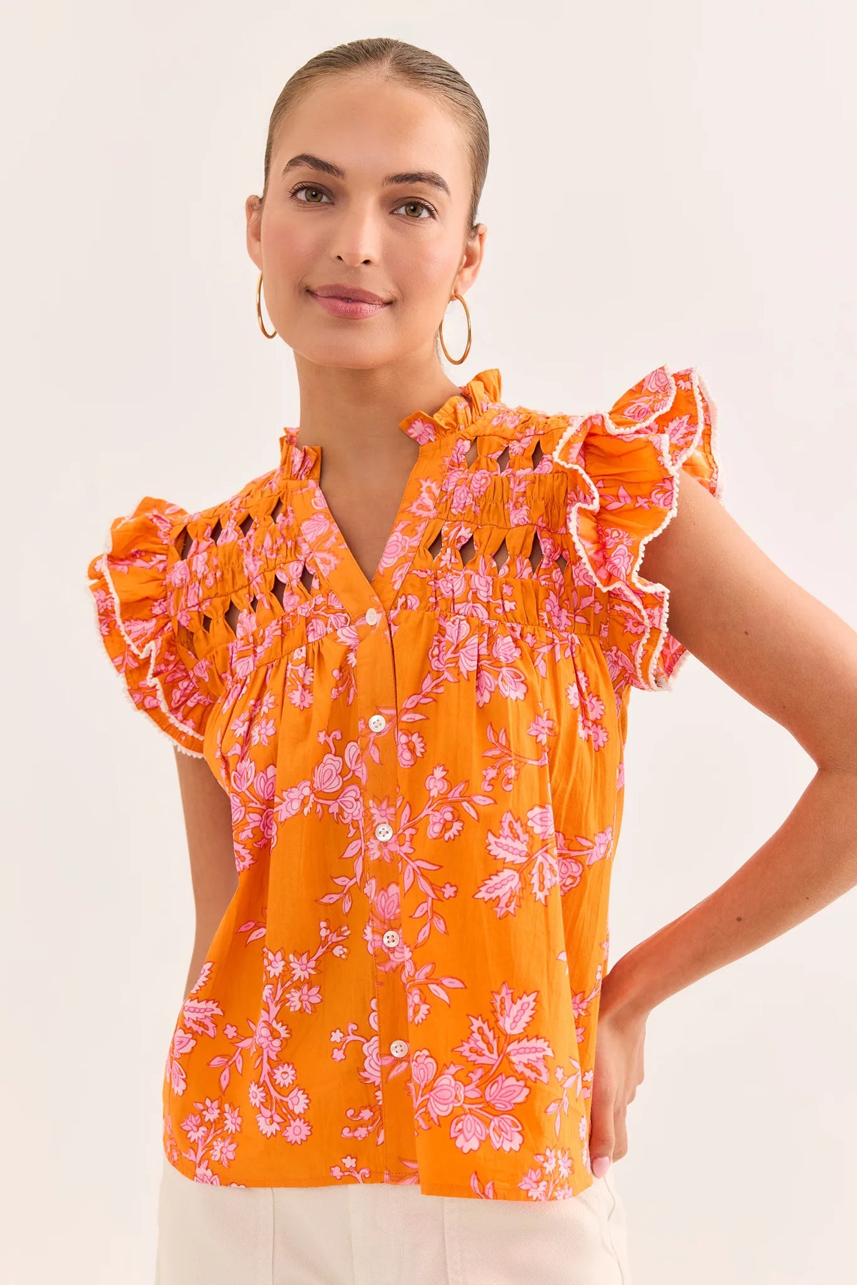 Woman wearing an orange floral blouse against a white background