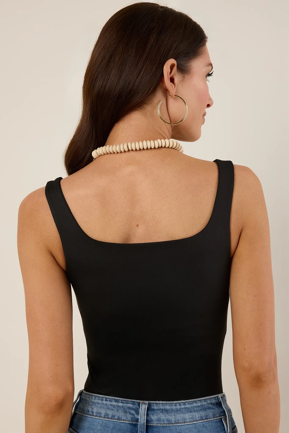 Bri Black Tank Bodysuit back view showing square back neckline and wide straps, tucked into jeans | Avara