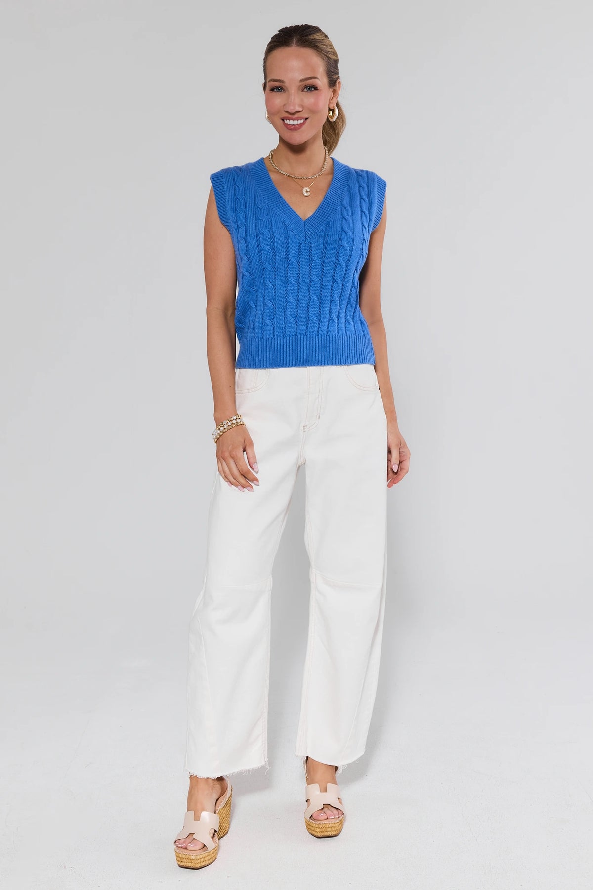 Women's blue sweater vest styled with white wide-leg jeans, full-length front view | Avara