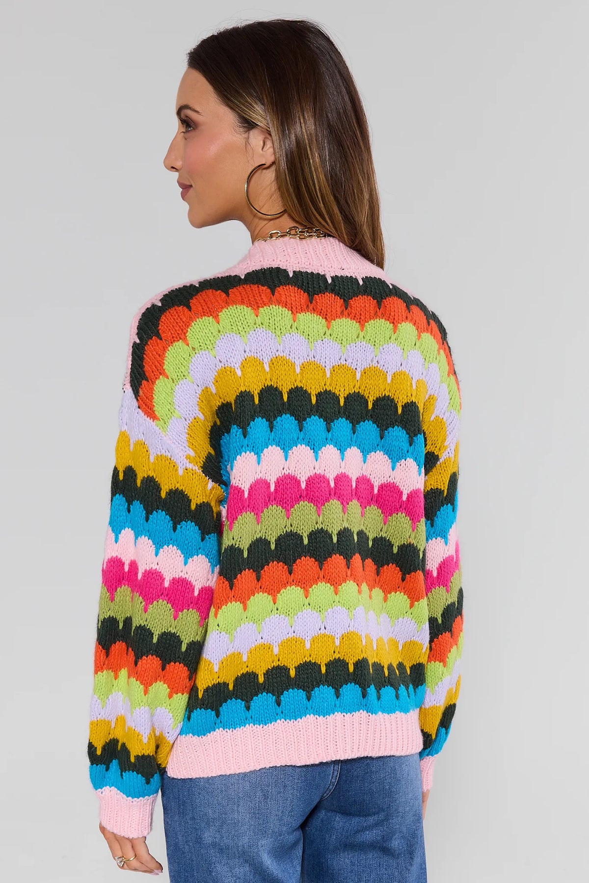 Woman wearing a colorful striped sweater against a plain background