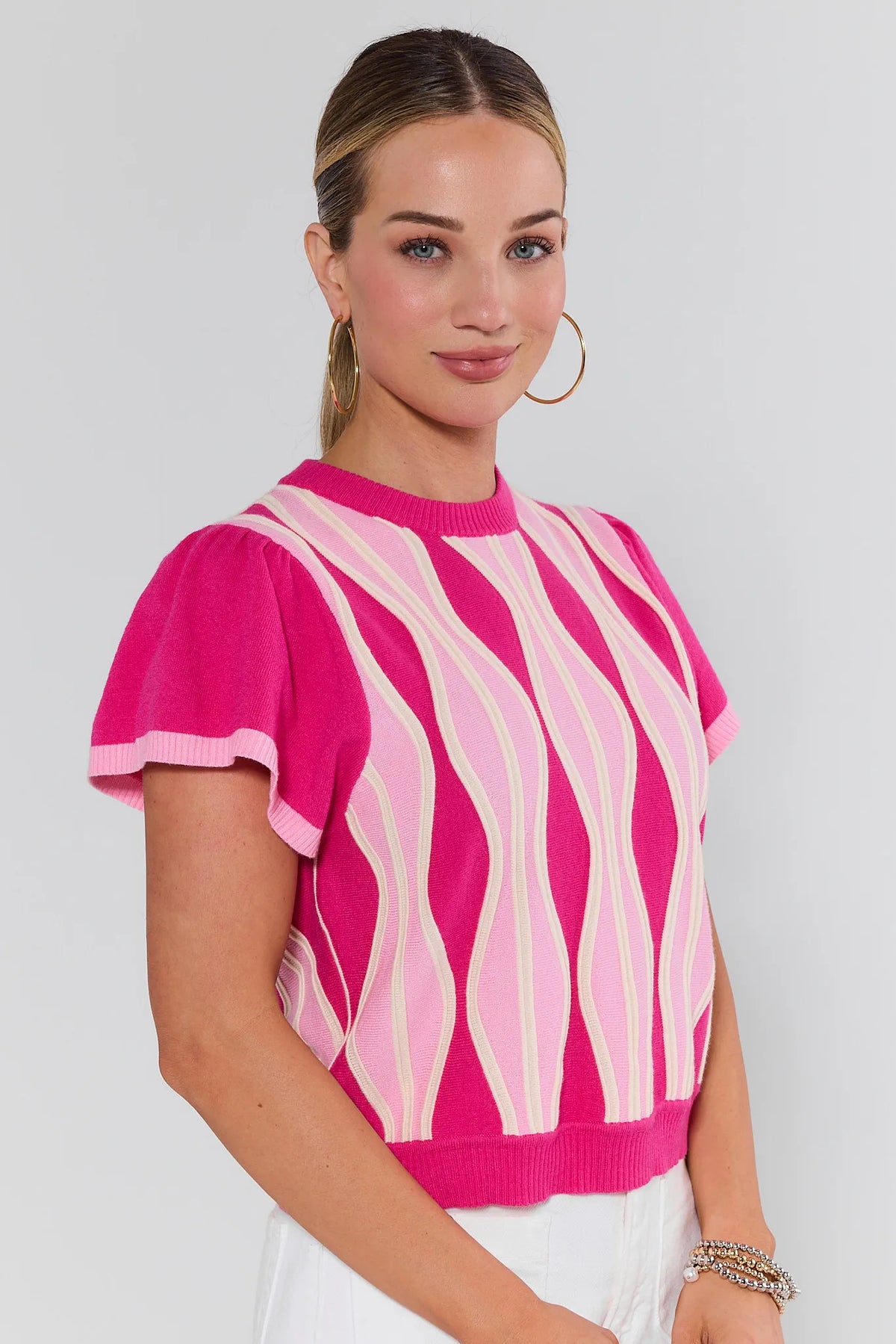 Woman wearing a pink and white patterned top against a plain background