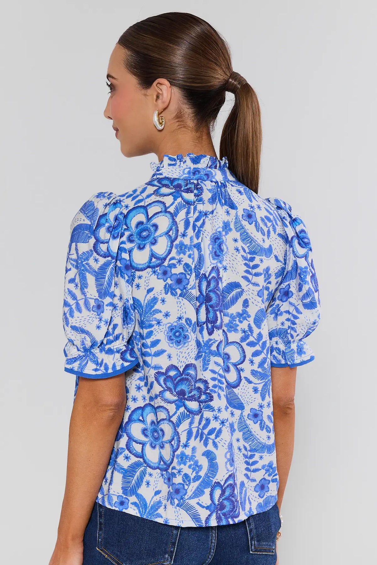 Woman wearing a blue floral blouse against a gray background