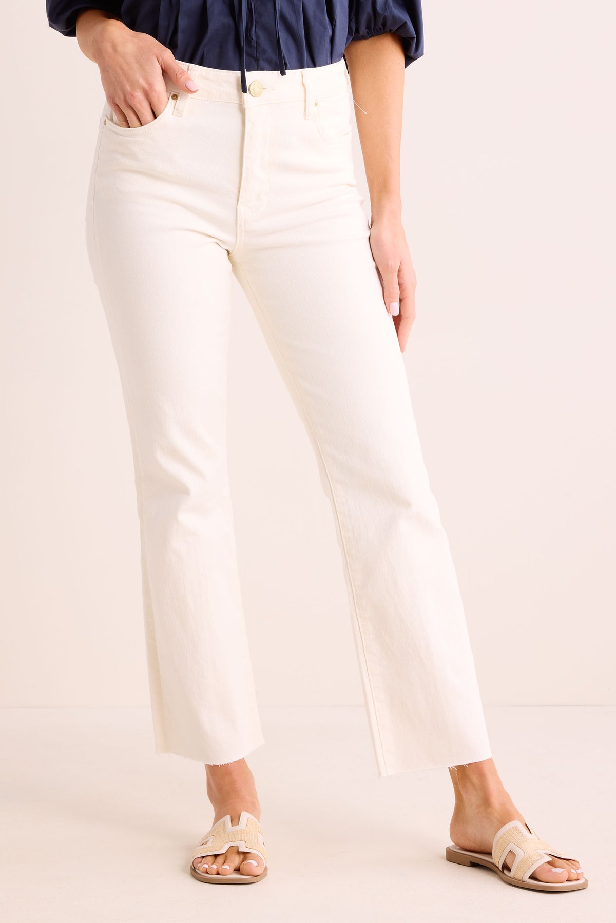 Kelsey Ecru Kick Flare Jeans high-waisted front view, raw hem, paired with navy top and woven sandals | Avara
