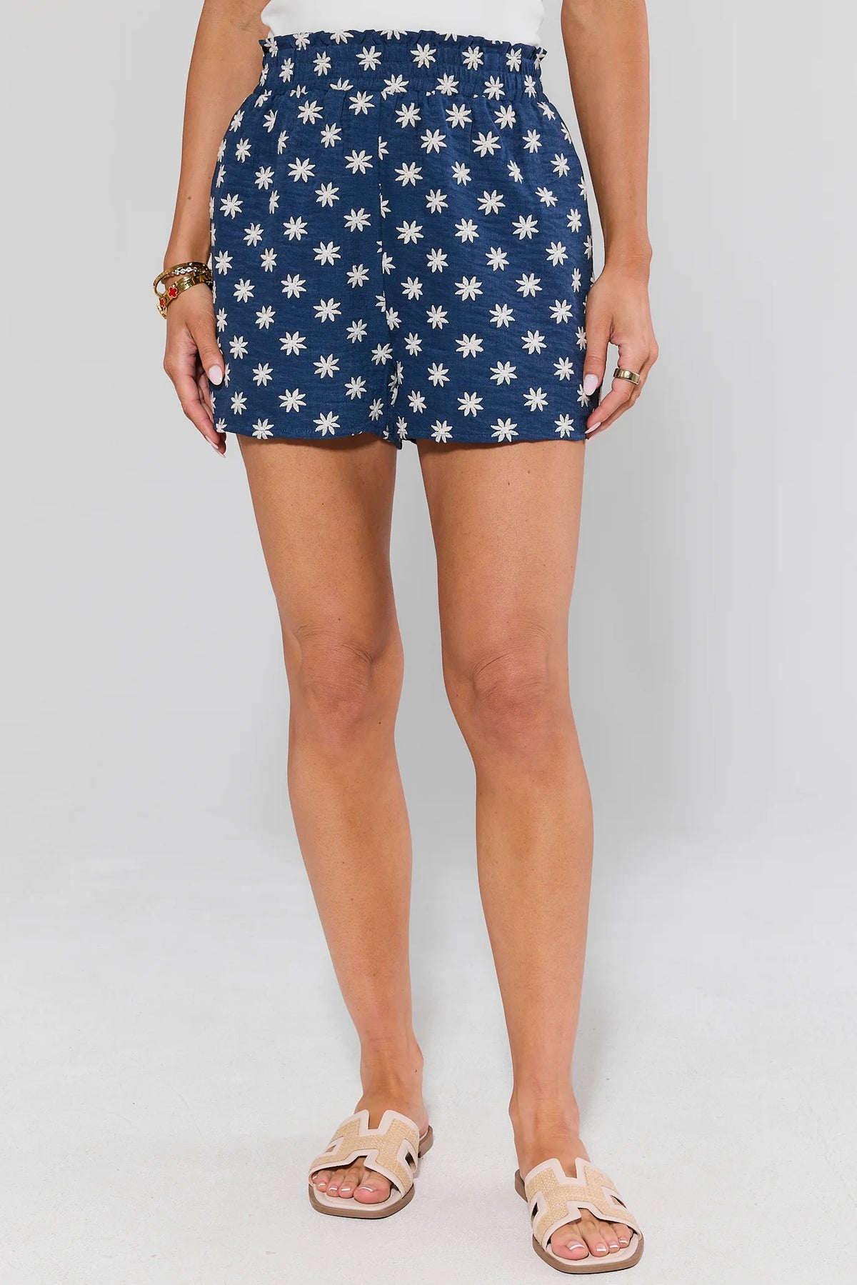 Navy blue and white floral embroidered shorts on model with sandals, front view | Avara