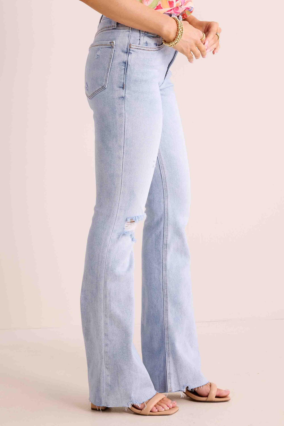 Phoebe Jeans light-wash kick-flare with distressed knee and frayed raw hem, side view | Avara
