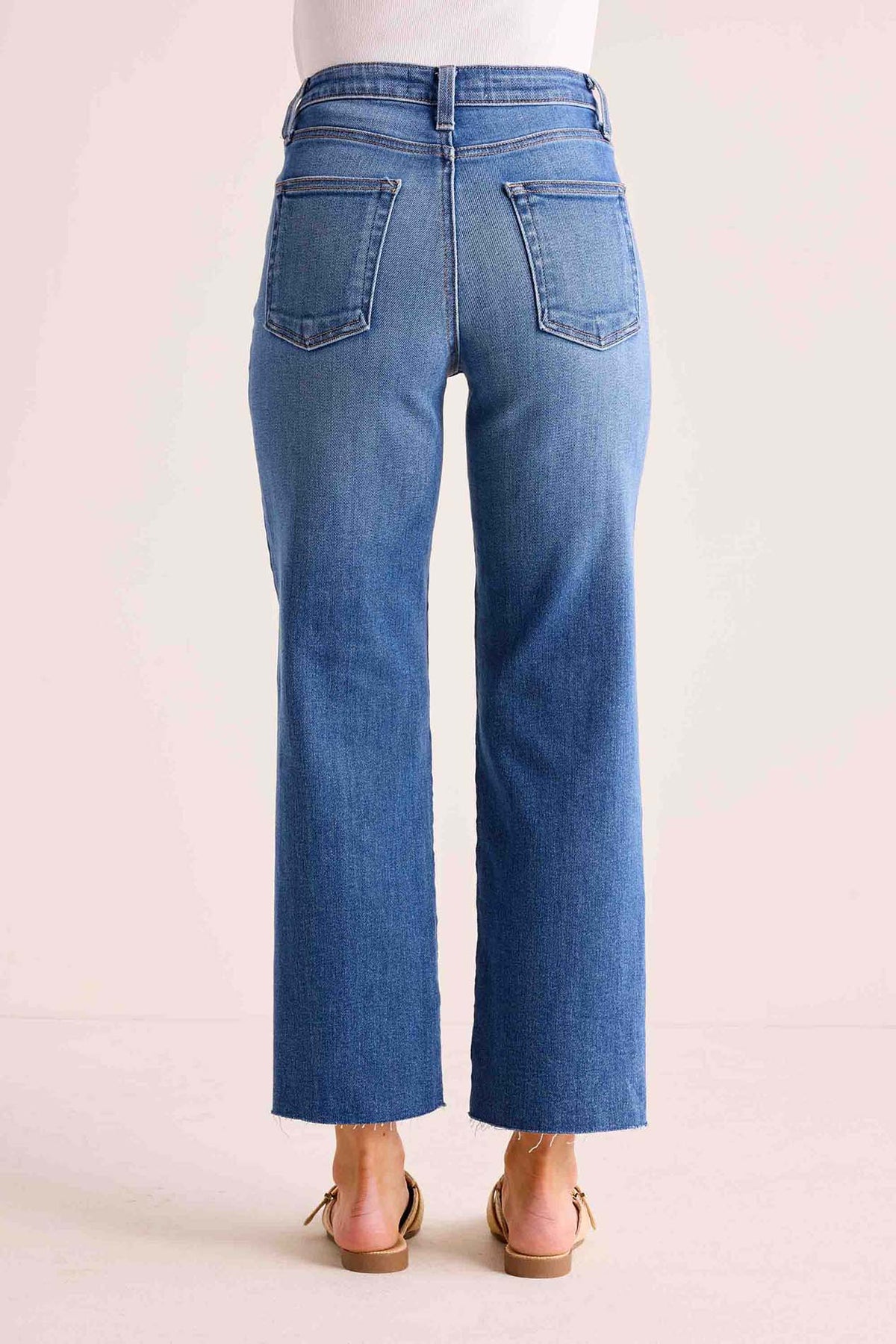 Melanie Medium Wash Straight Leg Jeans back patch pocket detail with raw frayed hem, high-rise fit, worn with tan flat sandals | Avara