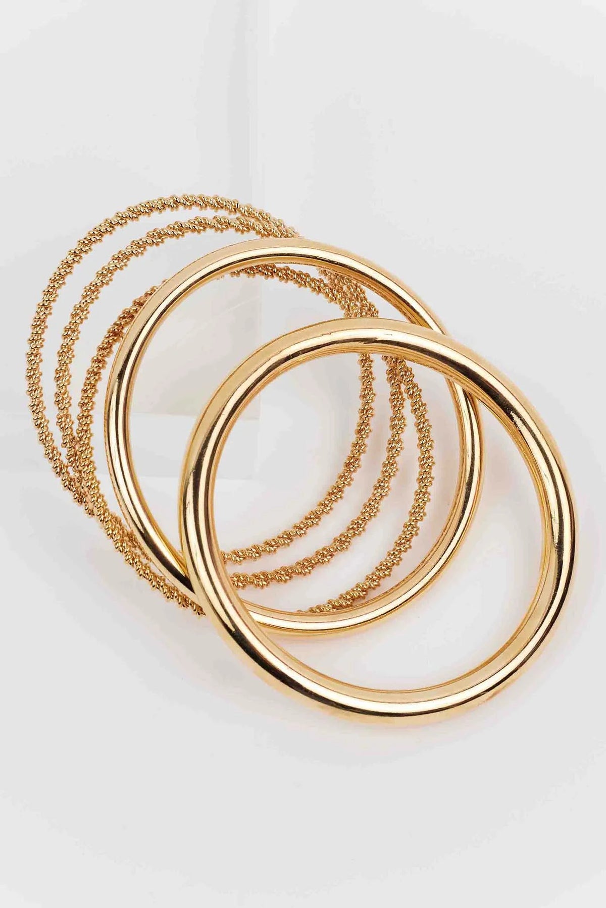 Sandra Gold Bangle Set featuring five slip-on bangles, combining smooth and rope-like textures in gold-tone metal for a versatile, polished look.