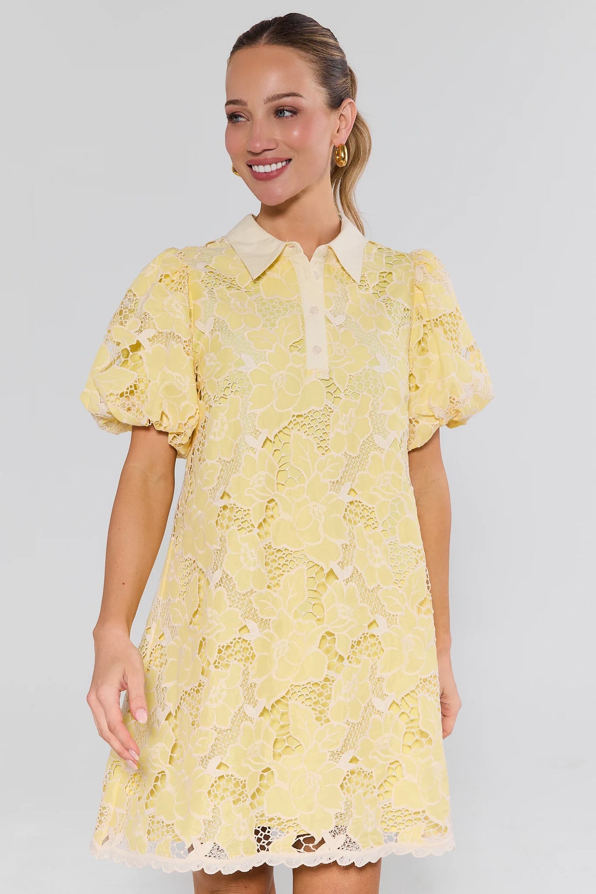 Woman wearing a yellow lace dress against a plain background