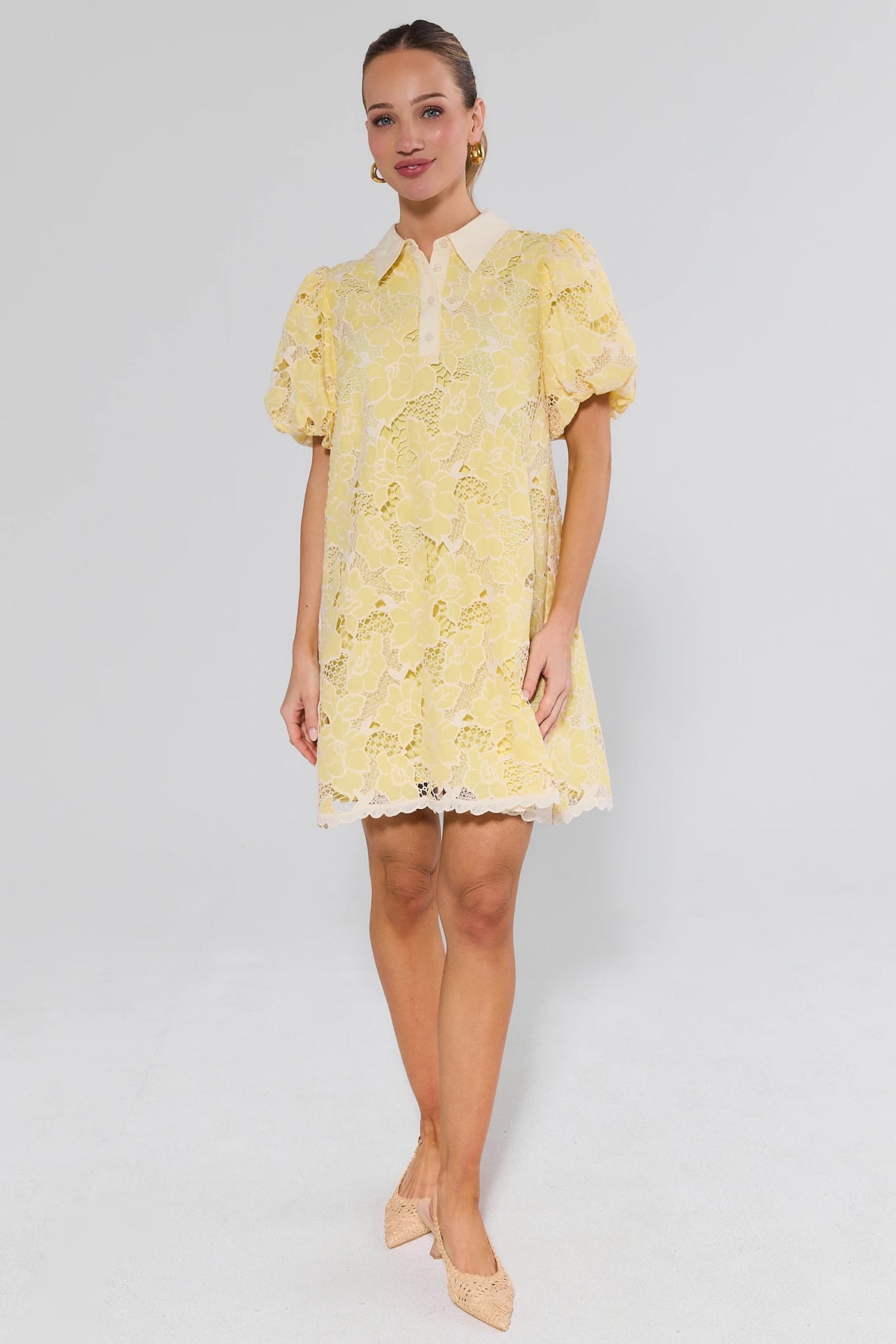 Woman wearing a yellow lace dress and heels on a white background