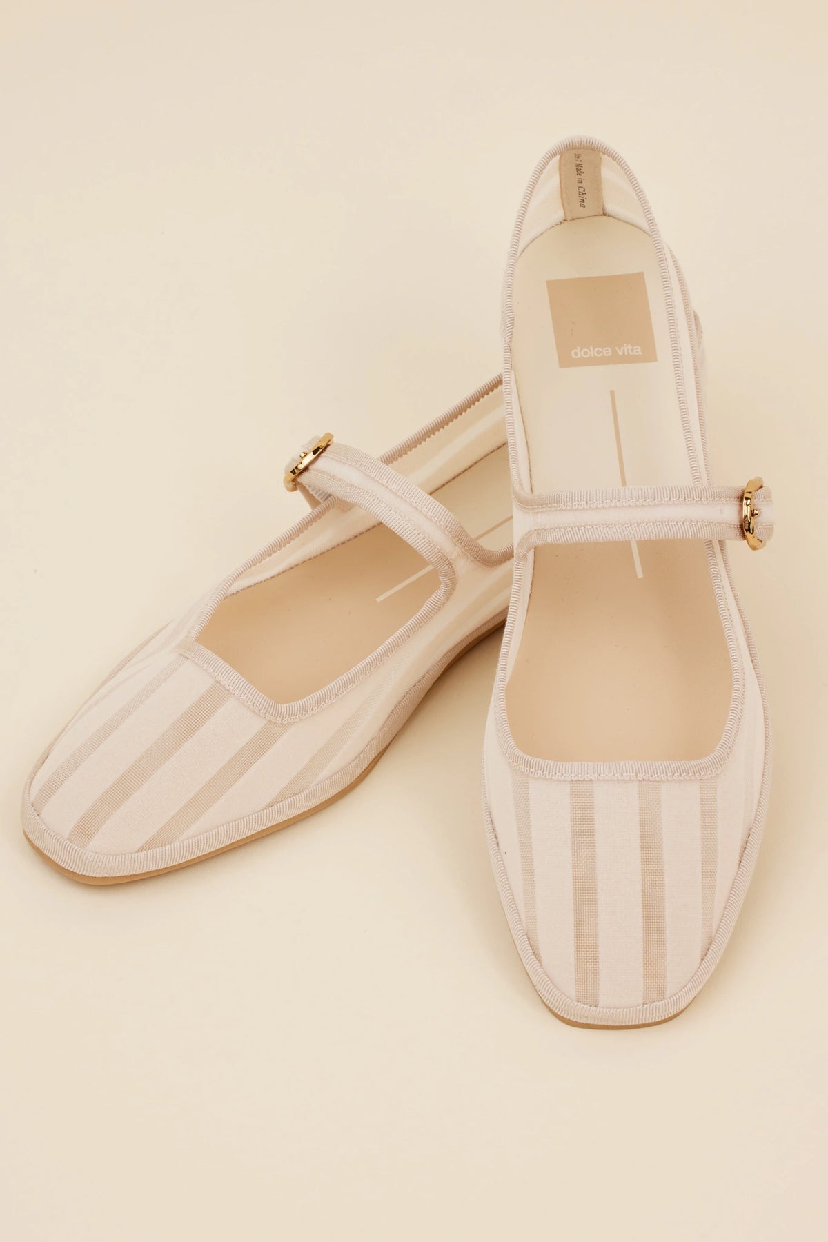Dolce Vita Tameka Flats - top-down view showing cream striped upper, gold buckle strap, and cushioned insole | Avara