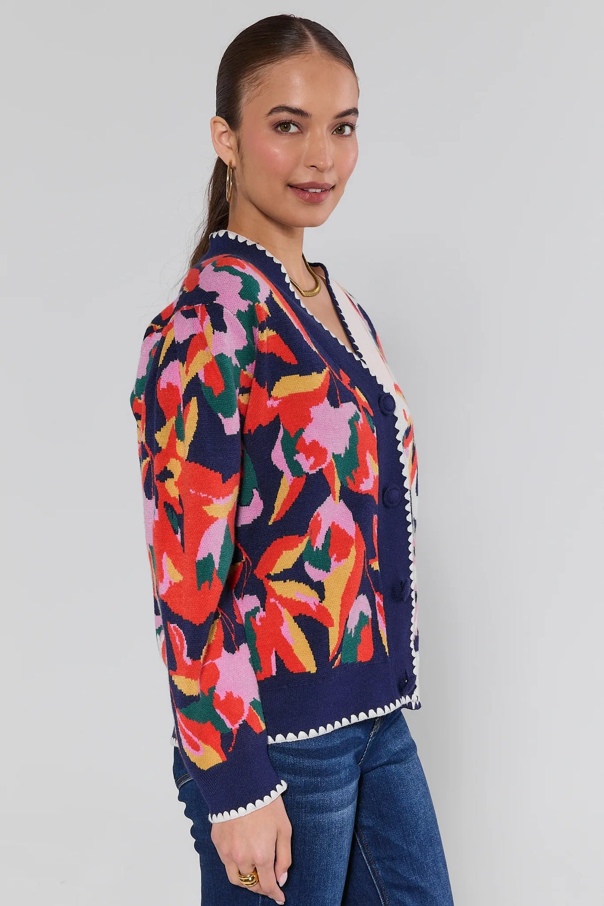 Leslie Navy Floral Cardigan side view showing bold floral knit print, scalloped hem, and navy button placket with jeans | Avara