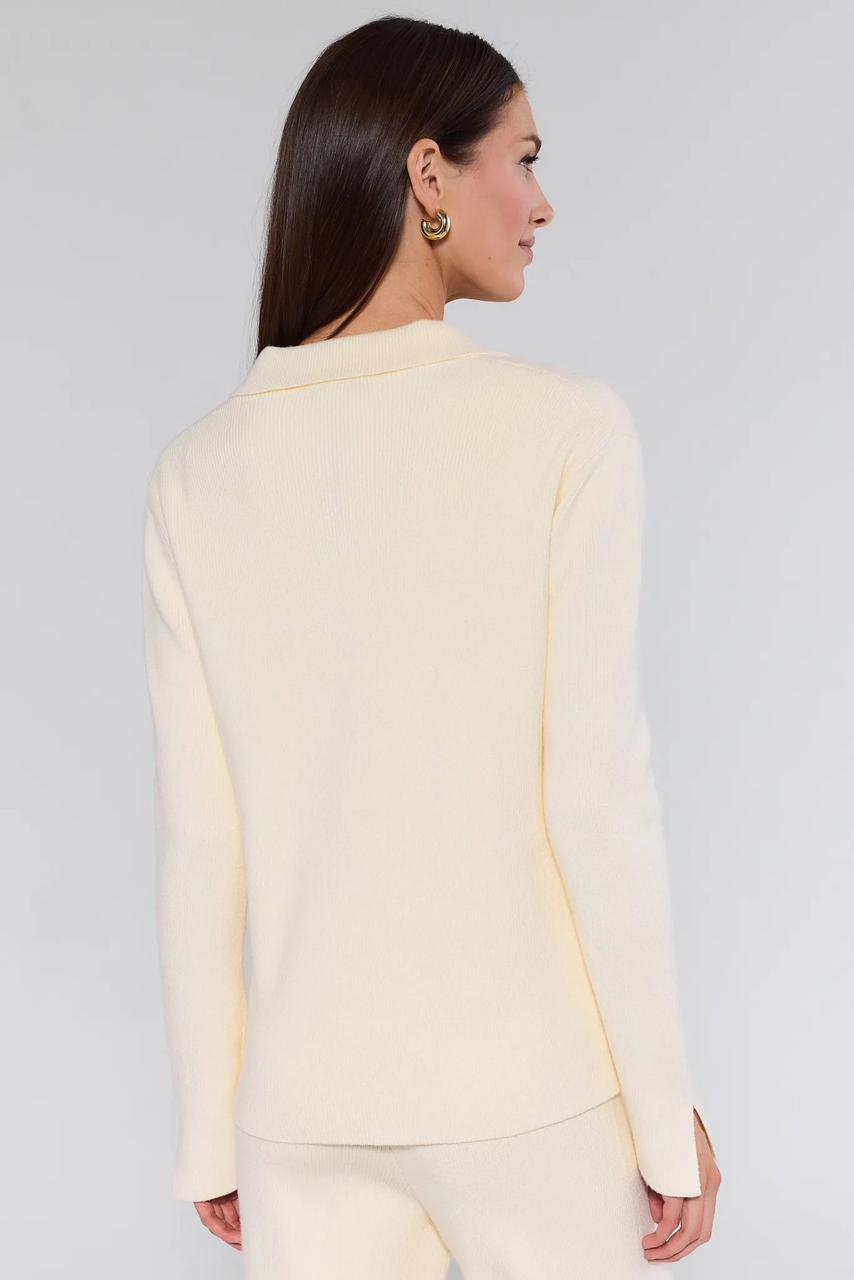 Woman in Elle Ivory Knit Sweater, featuring a relaxed fit, subtle polo collar, and split cuffs, paired with matching knit pants, showcasing a cozy, minimalist style.