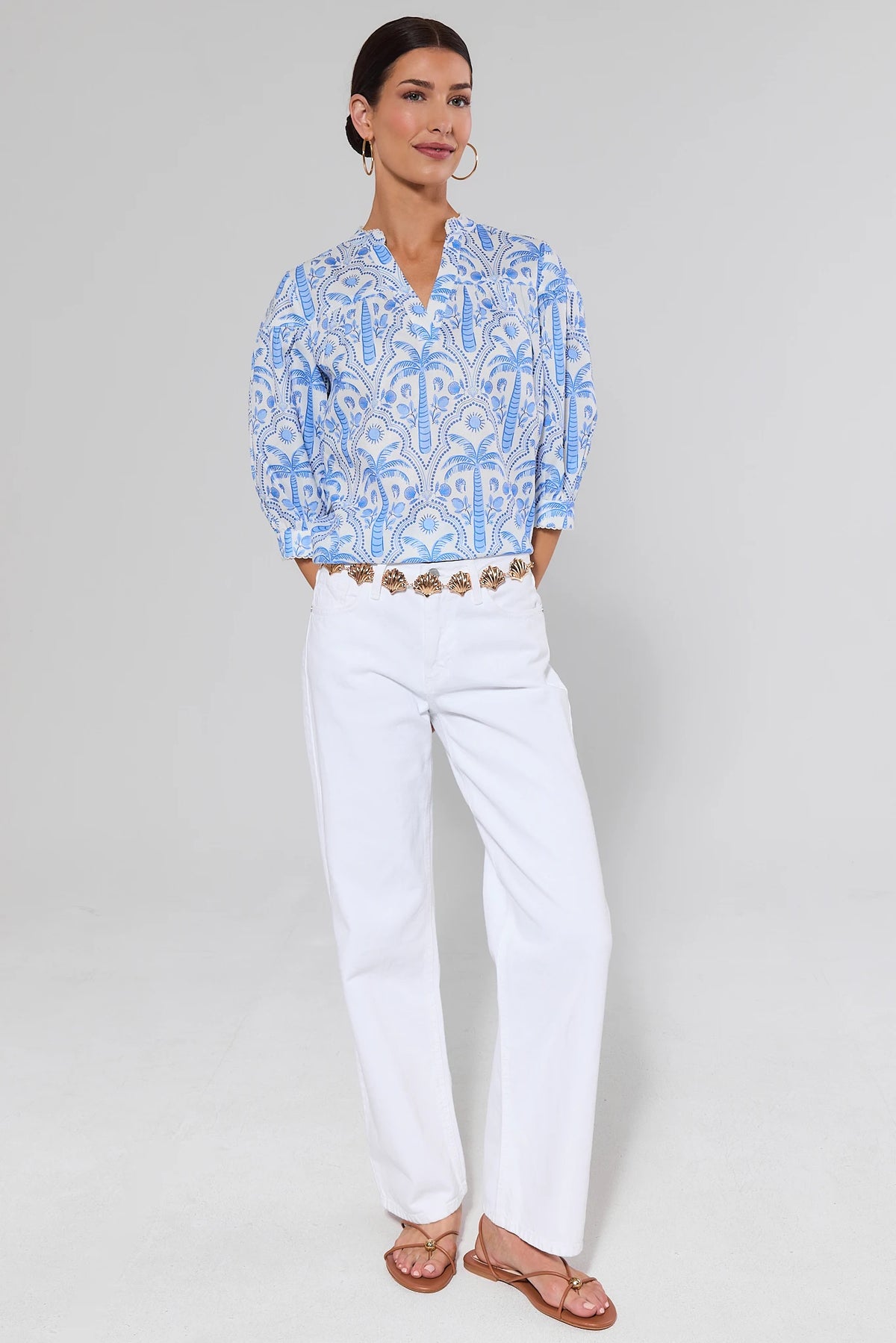 Woman wearing a blue patterned blouse and white jeans on a background