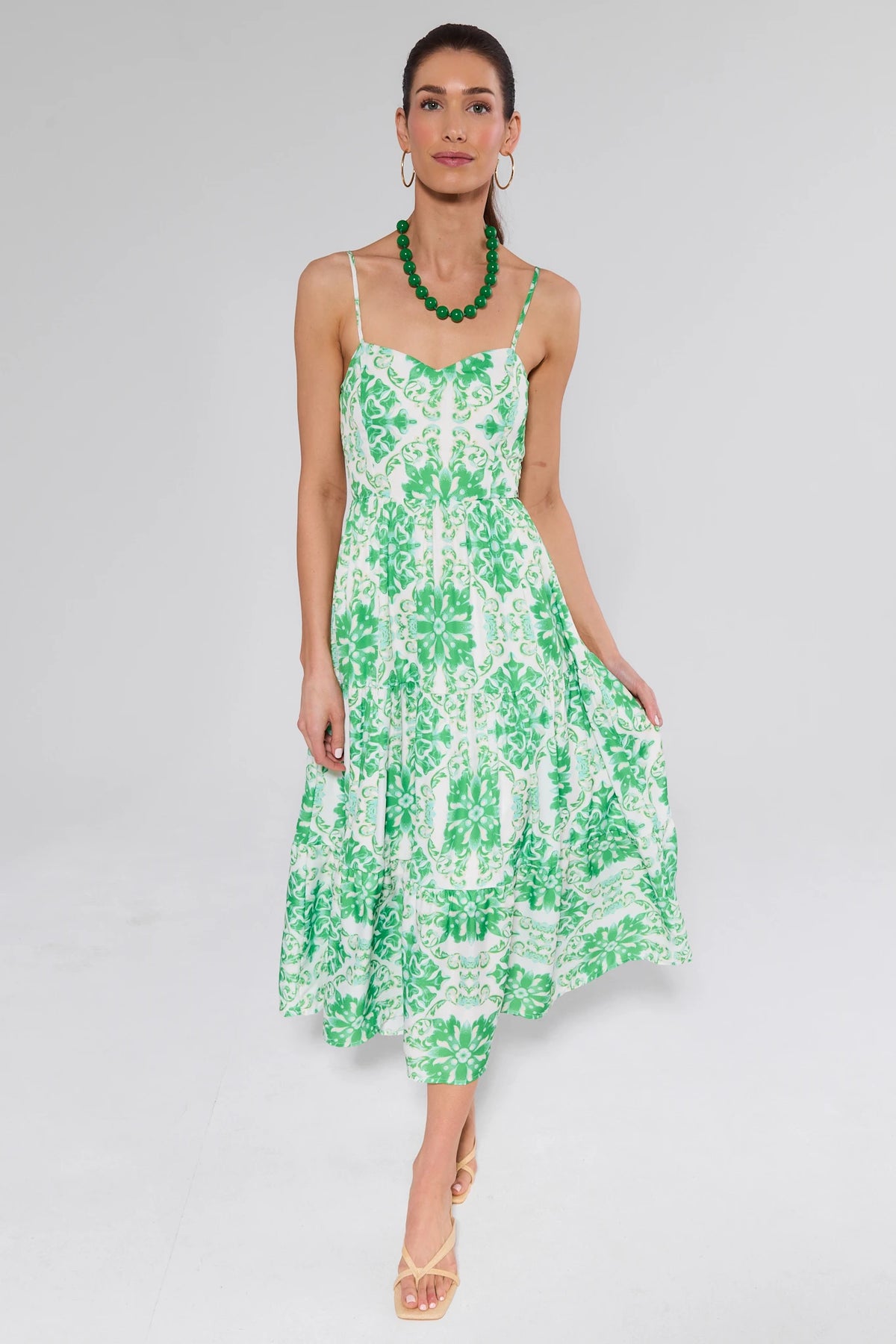 Model in Lori Green Printed Midi Dress with floral-medallion pattern, sweetheart neckline, and spaghetti straps. Styled with green necklace, hoop earrings, and nude heels.