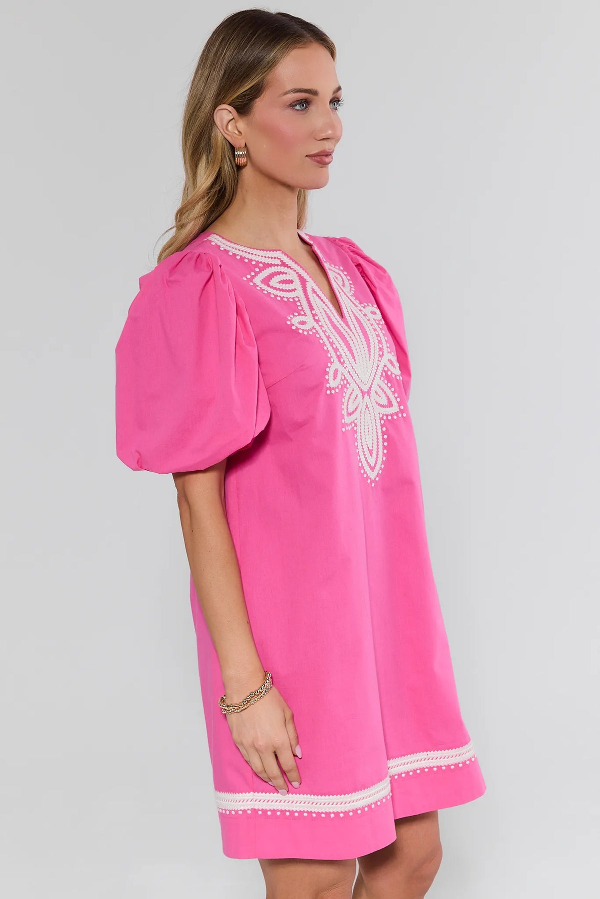 Pink embroidered short dress with white trim hem and puff sleeves on model - Side Profile | Avara