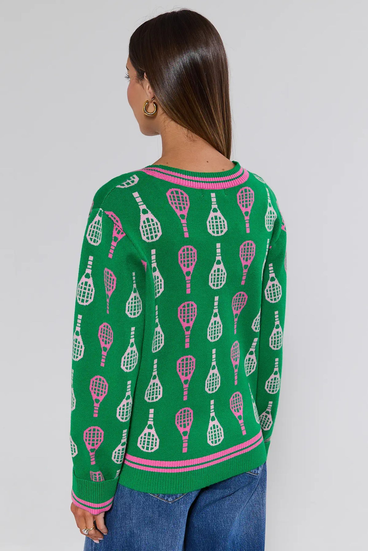 Green tennis cardigan with pink racket print, back view on model wearing jeans | Avara