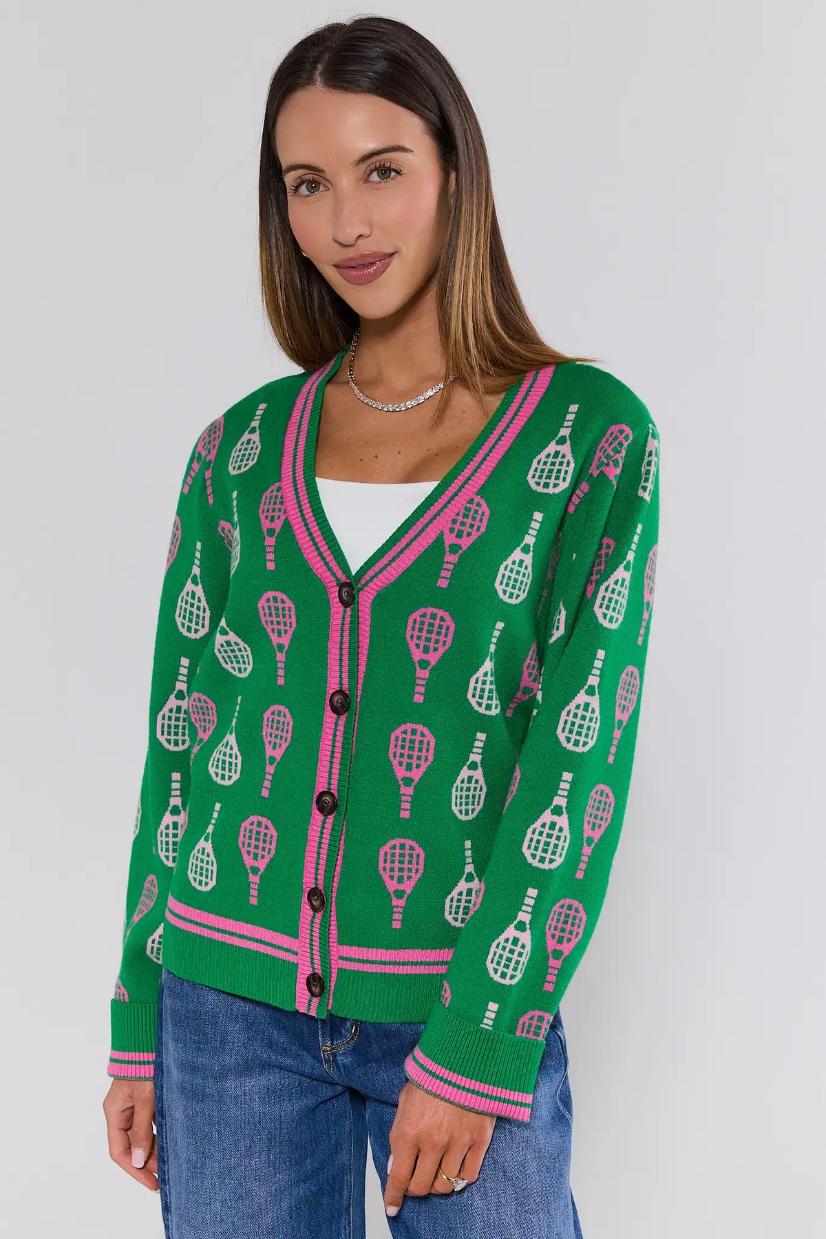 Green tennis racket print cardigan with pink trim, V-neck, front view on model with jeans | Avara