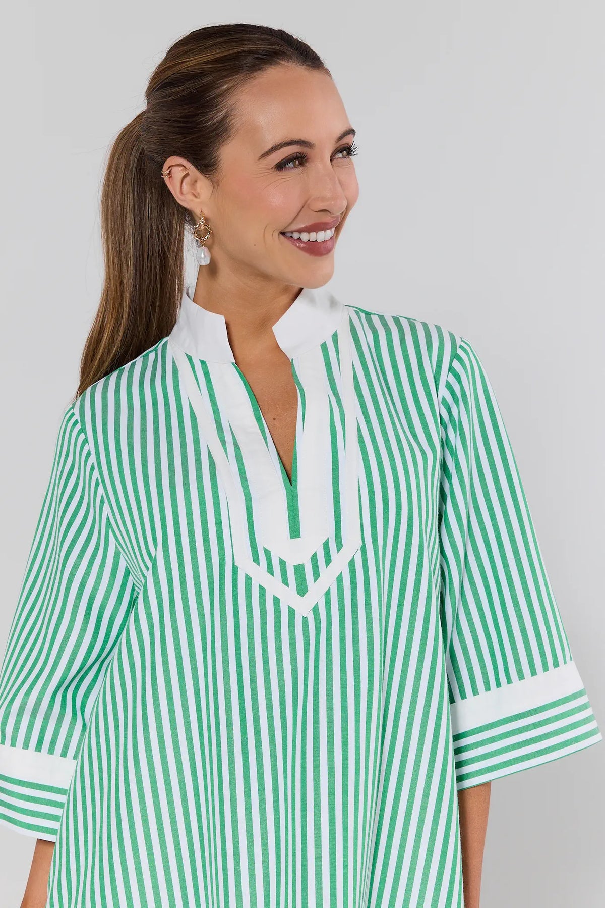 Woman wearing a green and white striped dress against a gray background
