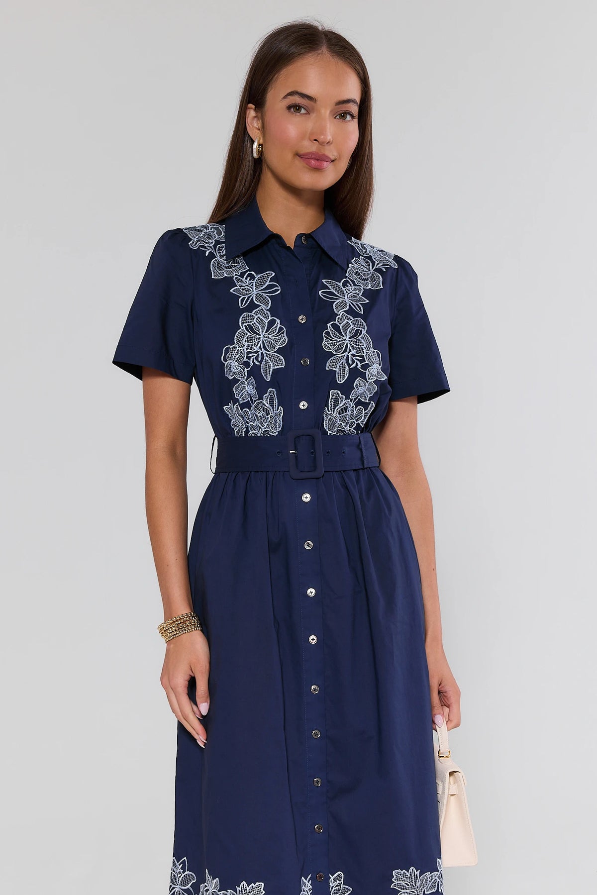 Woman in navy blue embroidered midi dress with white floral lace hem, A-line silhouette, side angle view | Avara