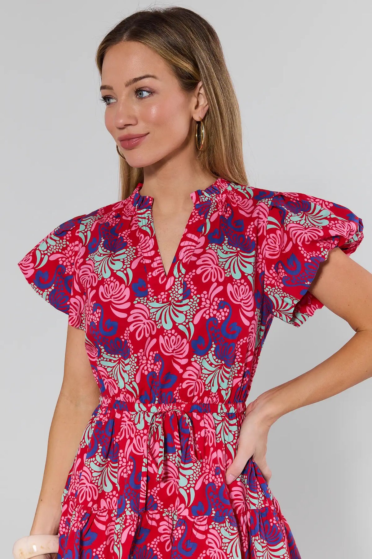 Woman wearing a red floral dress against a plain background