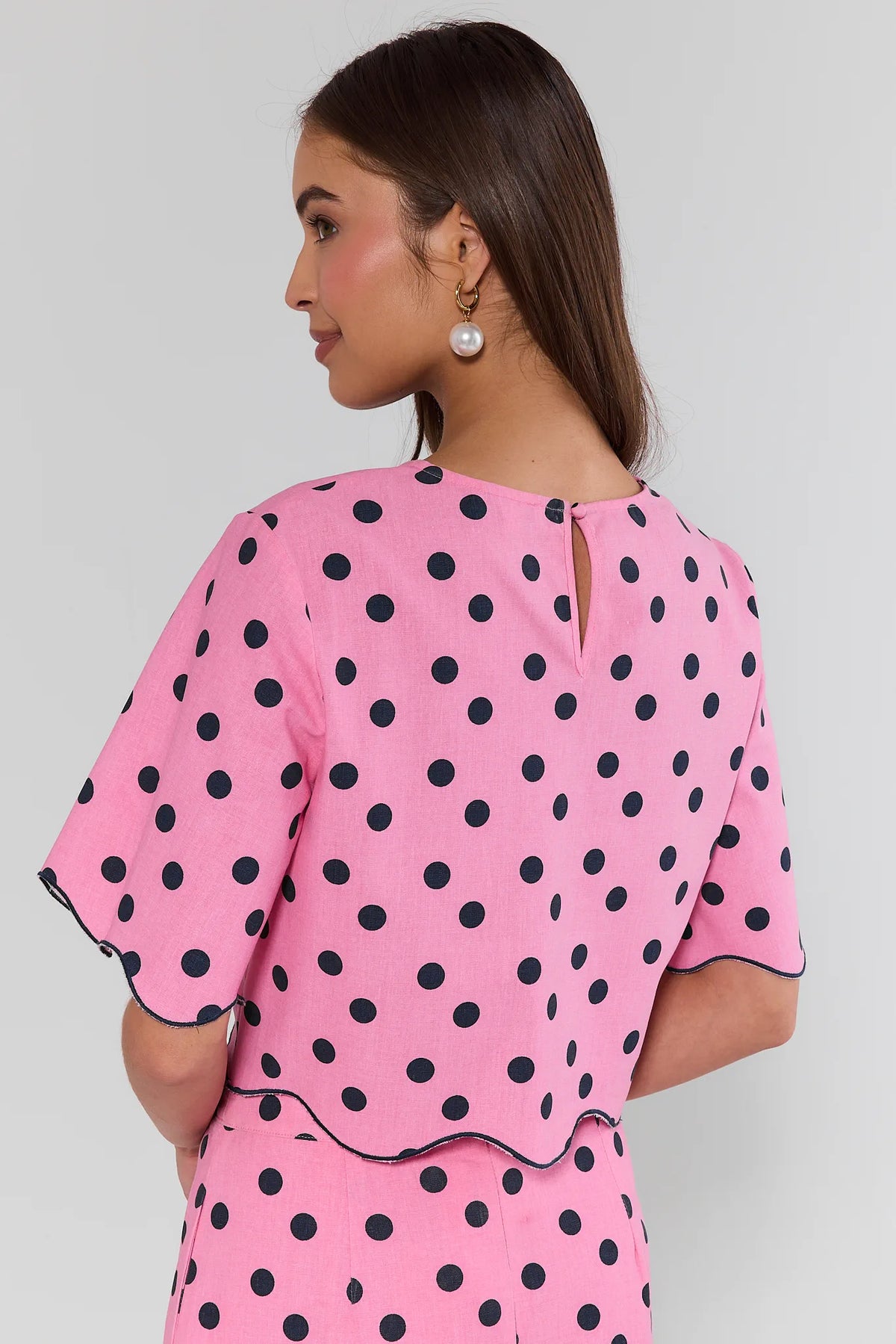 Maryl Pink Polka Dot Top - Back View showing keyhole neckline, navy dot print, and scalloped hem detail | Avara