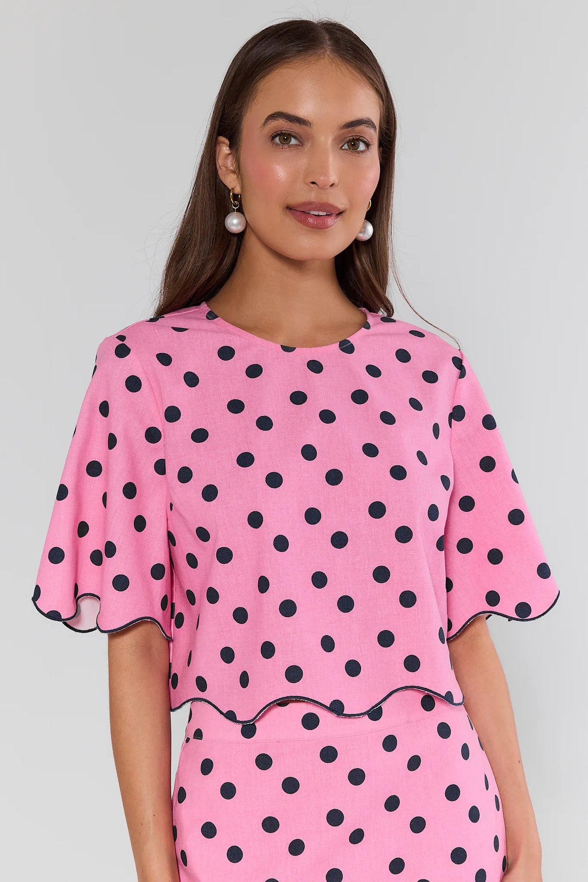 Maryl Pink Polka Dot Top - Front Close-Up, round neckline and navy dot print with scalloped hem detail | Avara