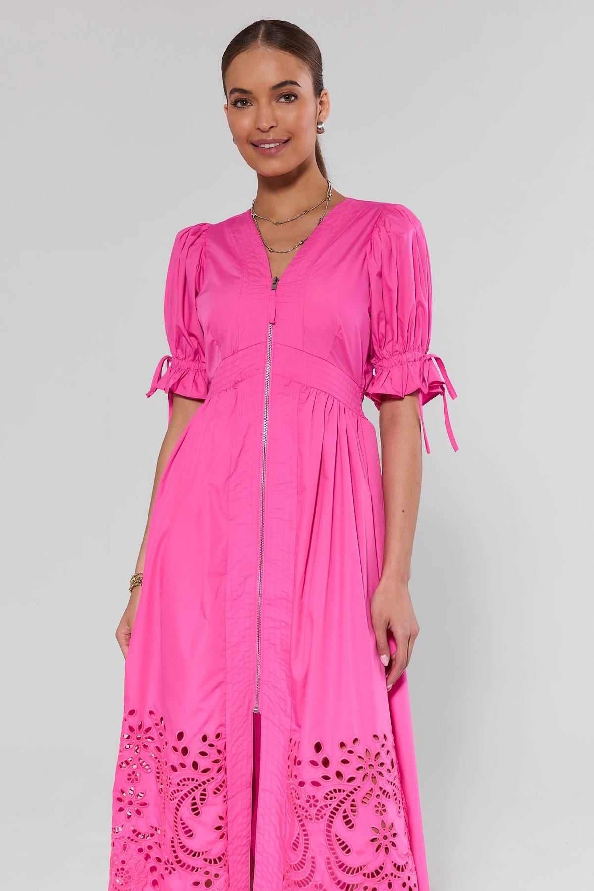 Woman wearing a bright dress with lace detailing on a plain background