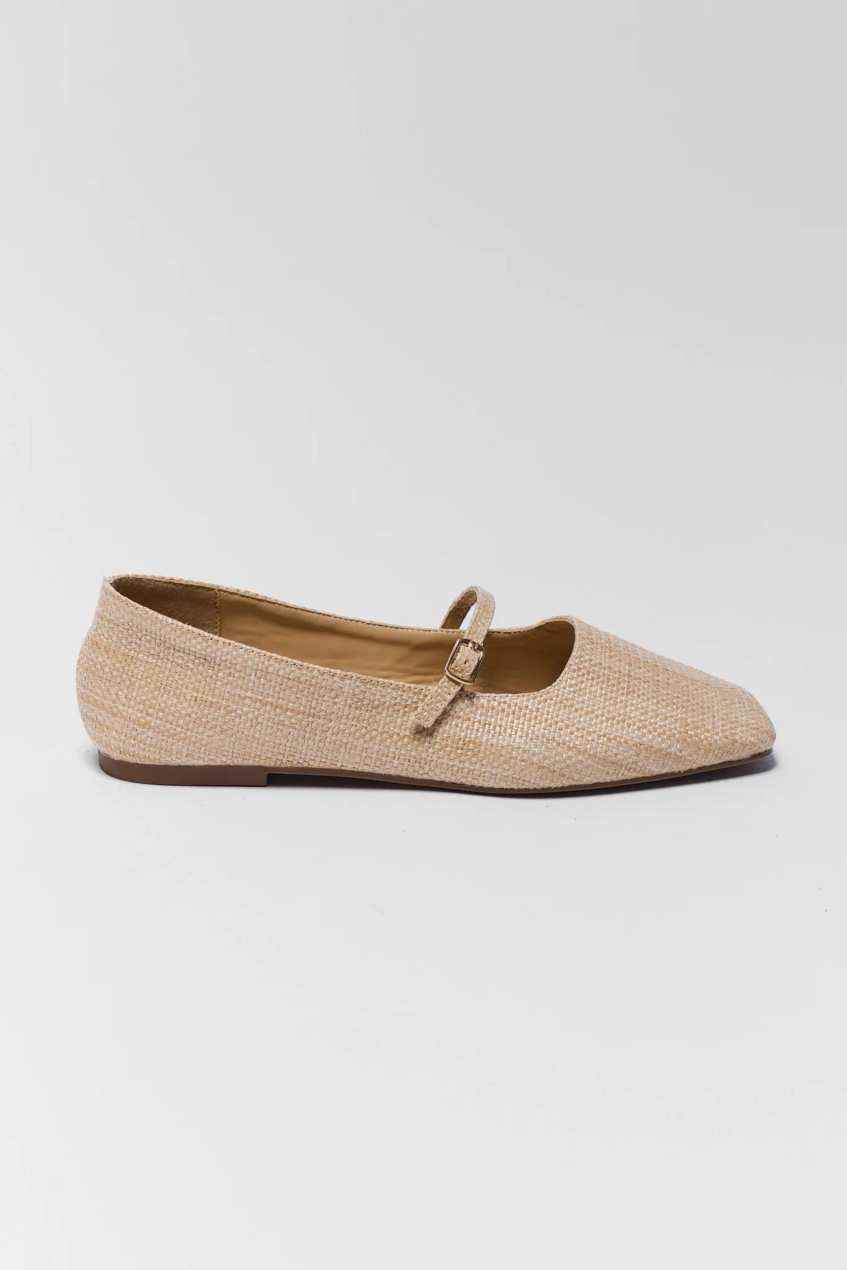Beige flat shoe with a strap on a light gray background