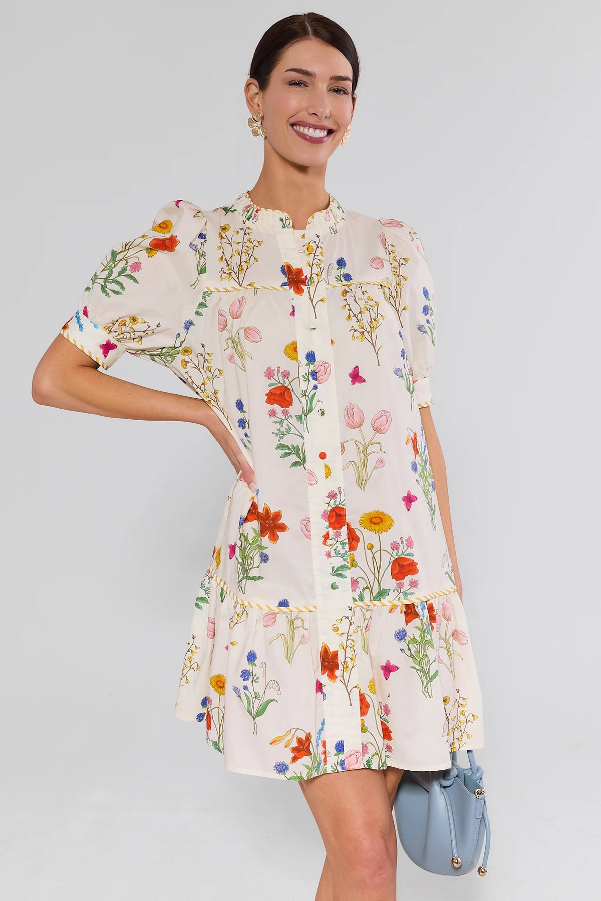 Woman wearing white floral drop waist dress with puff sleeves, front view, styled with blue bucket bag | Avara