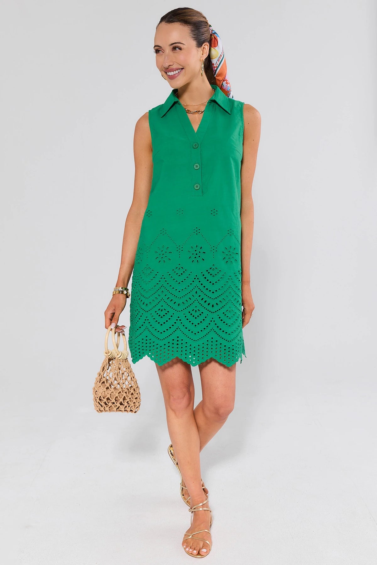 Woman wearing a green dress with a textured pattern and gold shoes on a white background