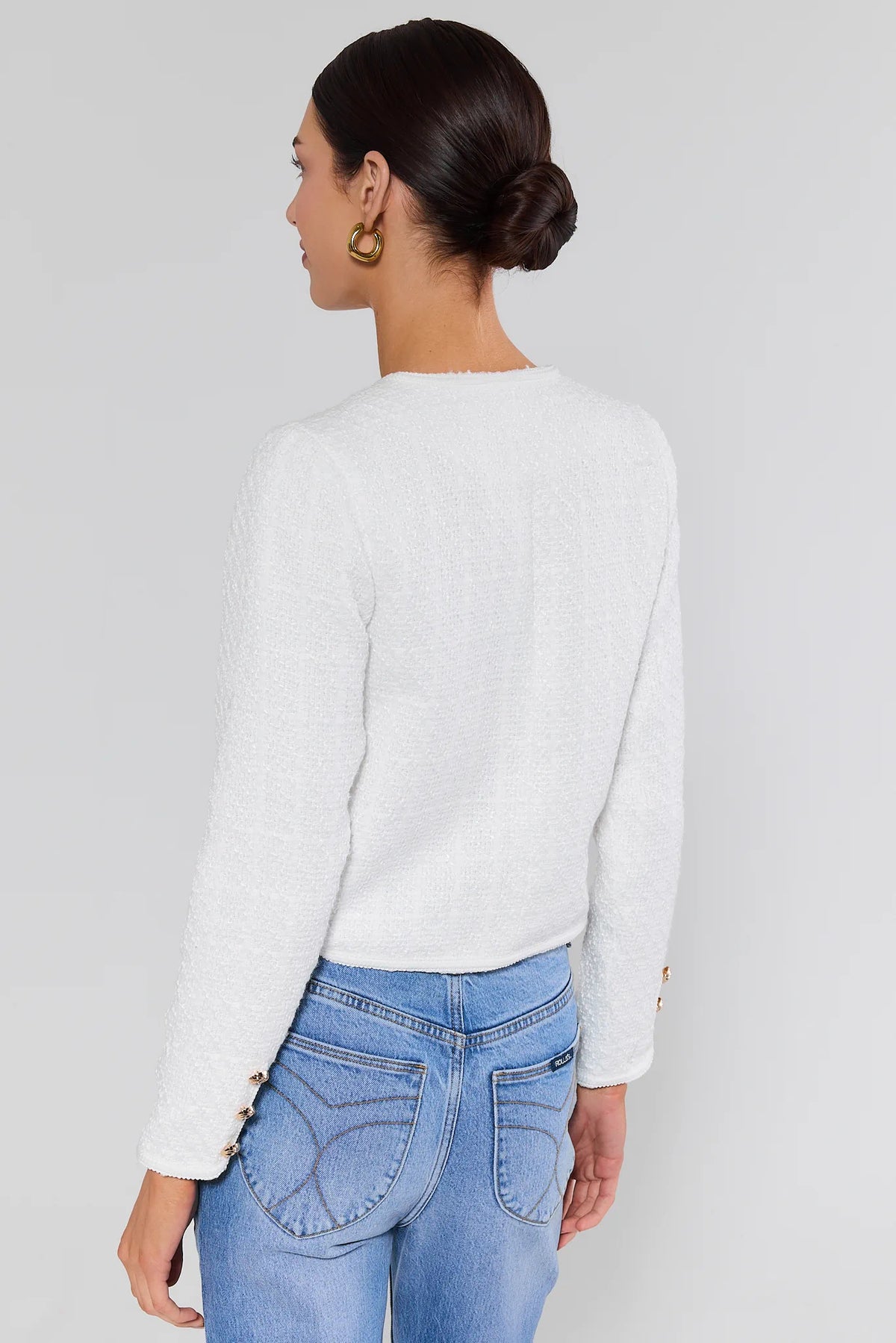 Woman wearing white tweed knit cardigan with gold cuff buttons and blue jeans - Back View | Avara