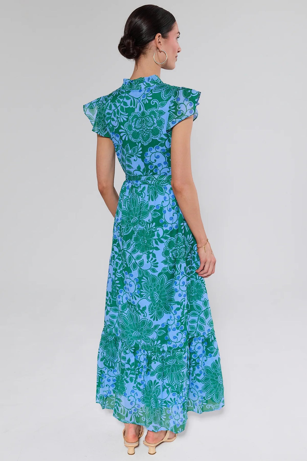 Woman wearing a blue and green floral dress on a white background
