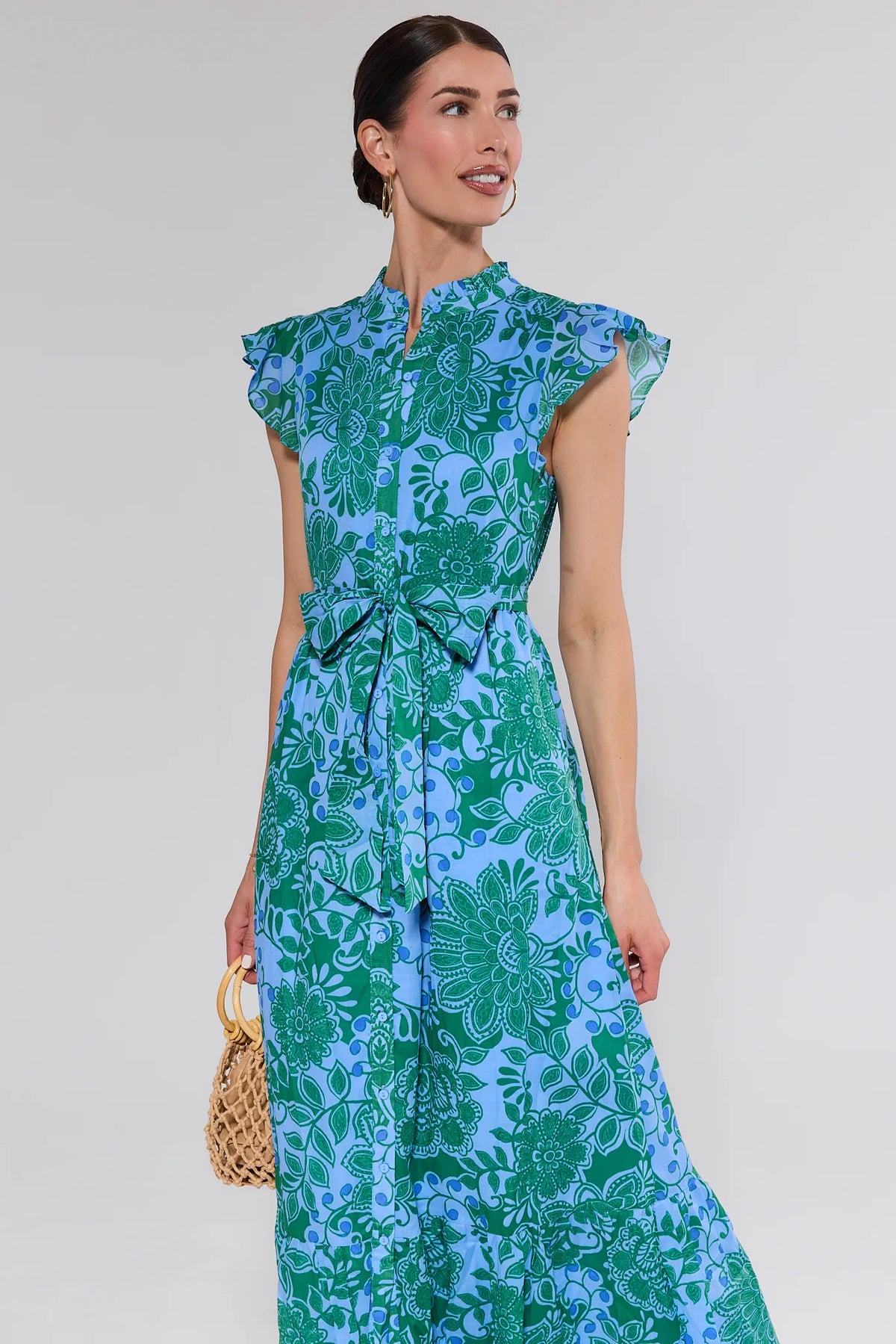 Woman wearing a green and blue floral dress against a white background