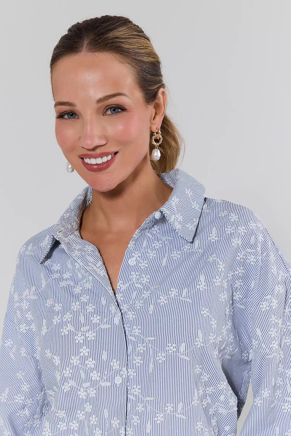 Woman wearing a blue blouse against a plain background close up
