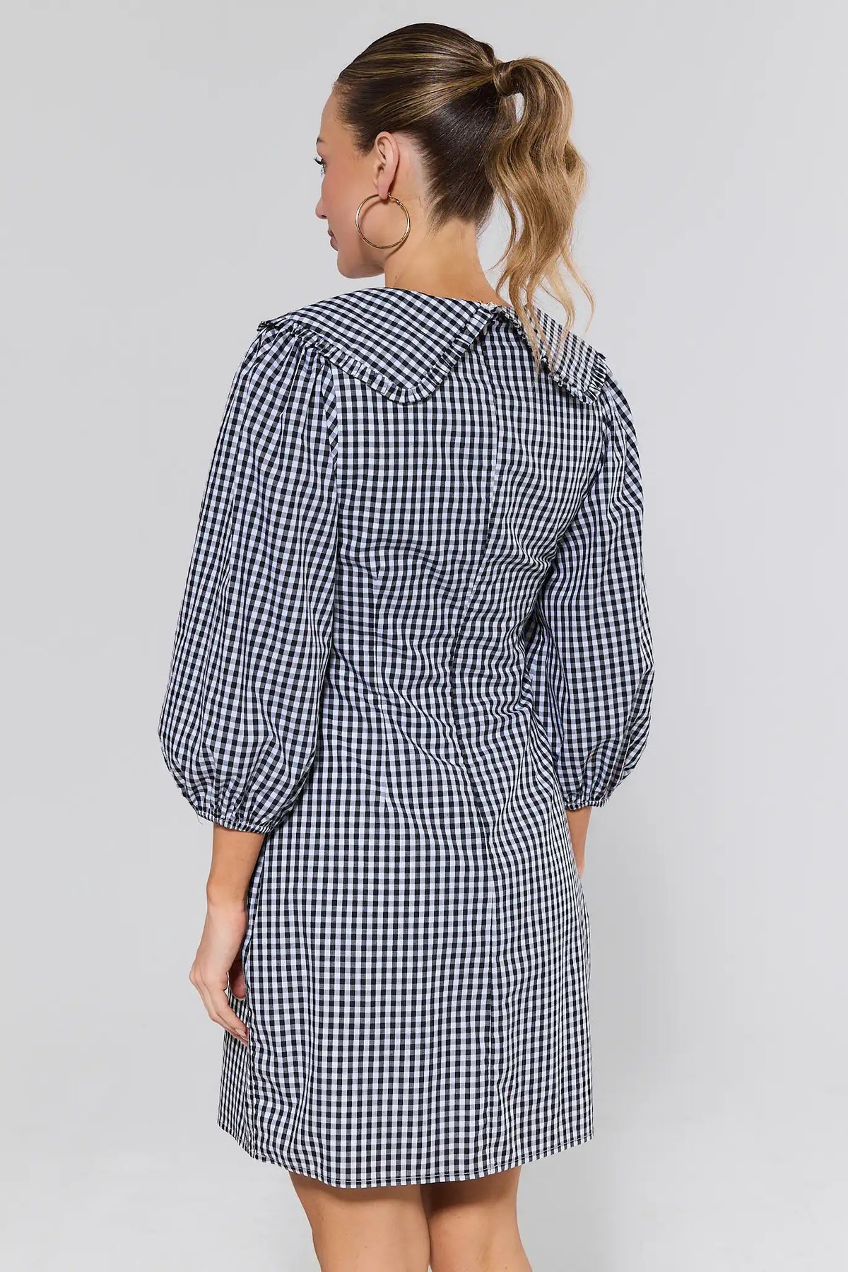 Woman wearing black gingham short dress with oversized Peter Pan collar - Back View | Avara