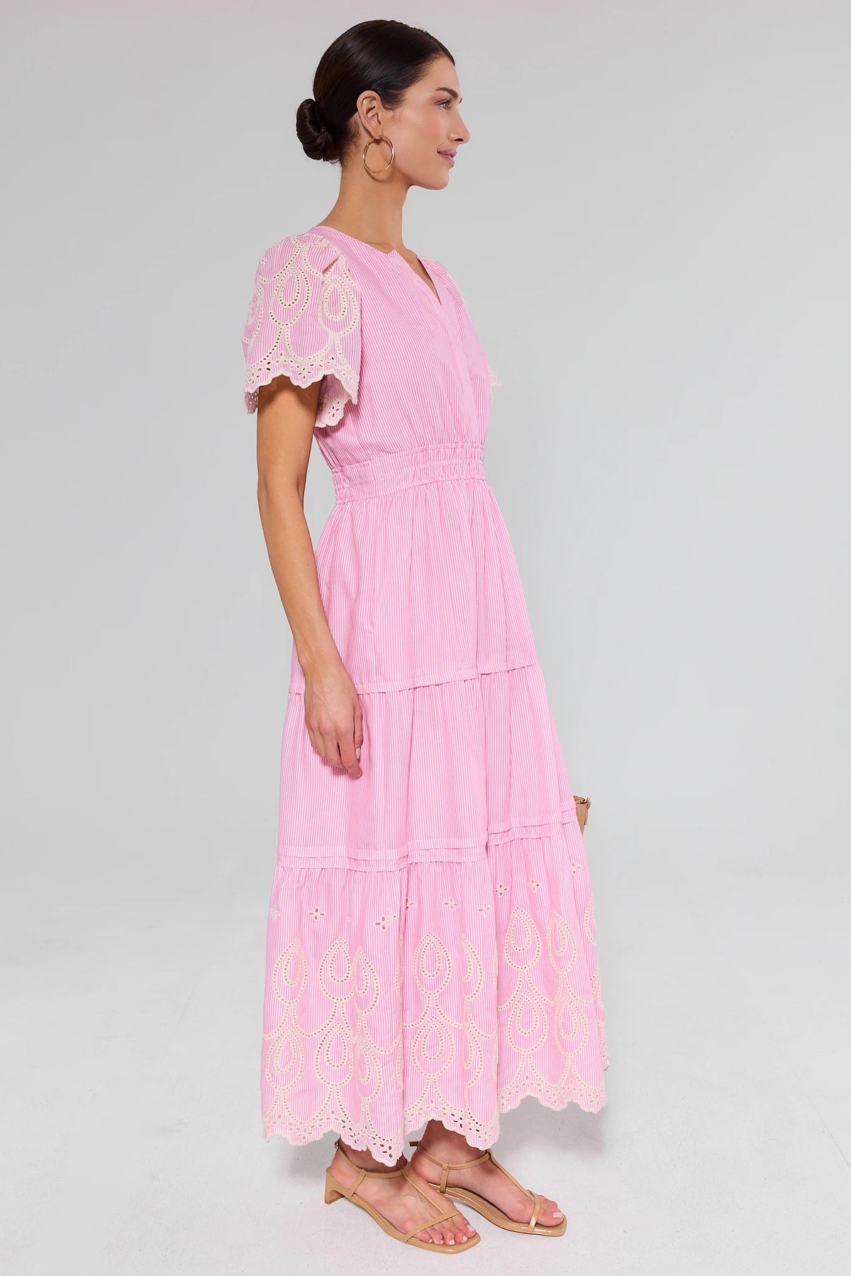 Woman wearing a pink dress with lace details on a white background and heels