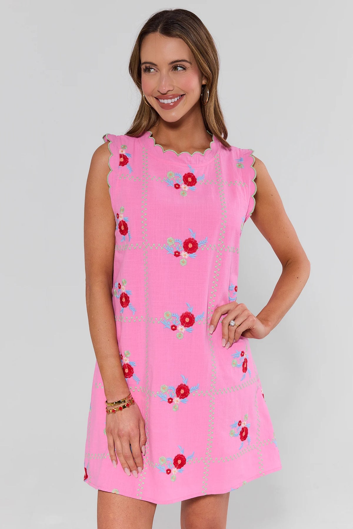 Woman wearing a pink dress with floral patterns on a plain background