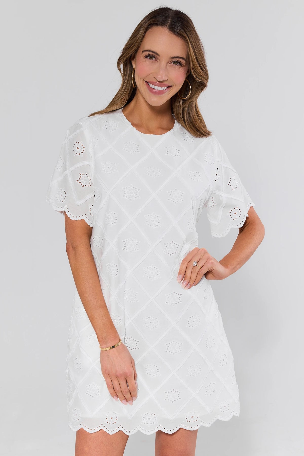 Woman wearing a white lace dress against a plain background