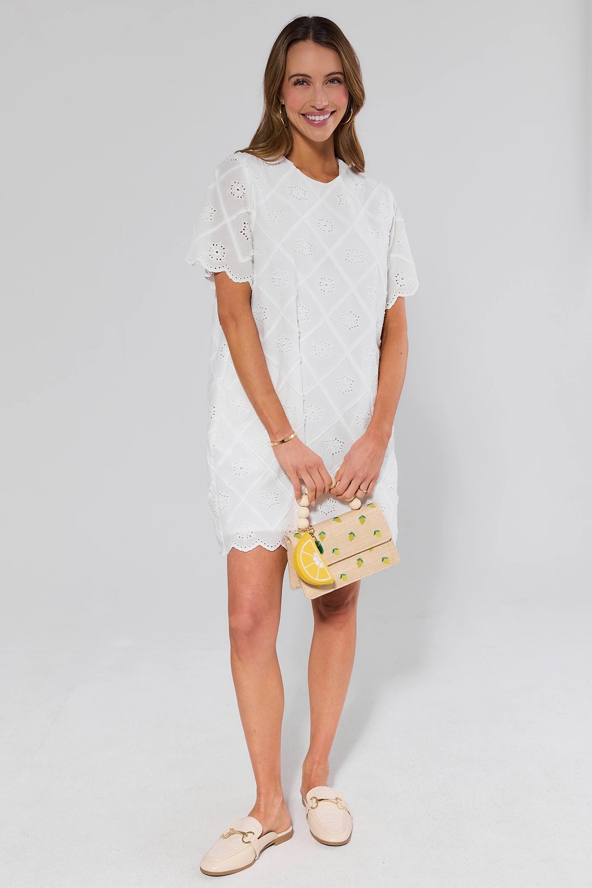 Woman wearing a white dress holding a yellow handbag against a plain background