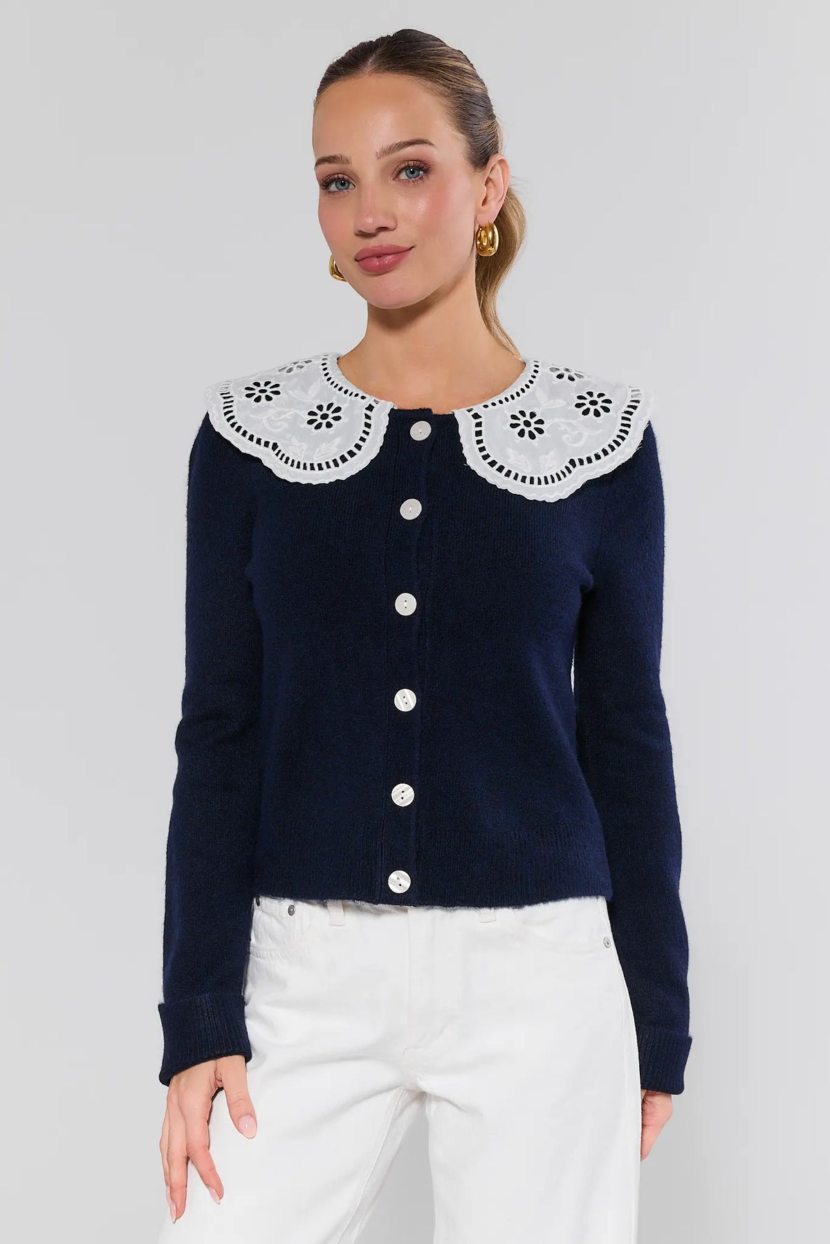 Woman wearing navy eyelet cardigan with white Peter Pan collar and pearl buttons - Front View | Avara