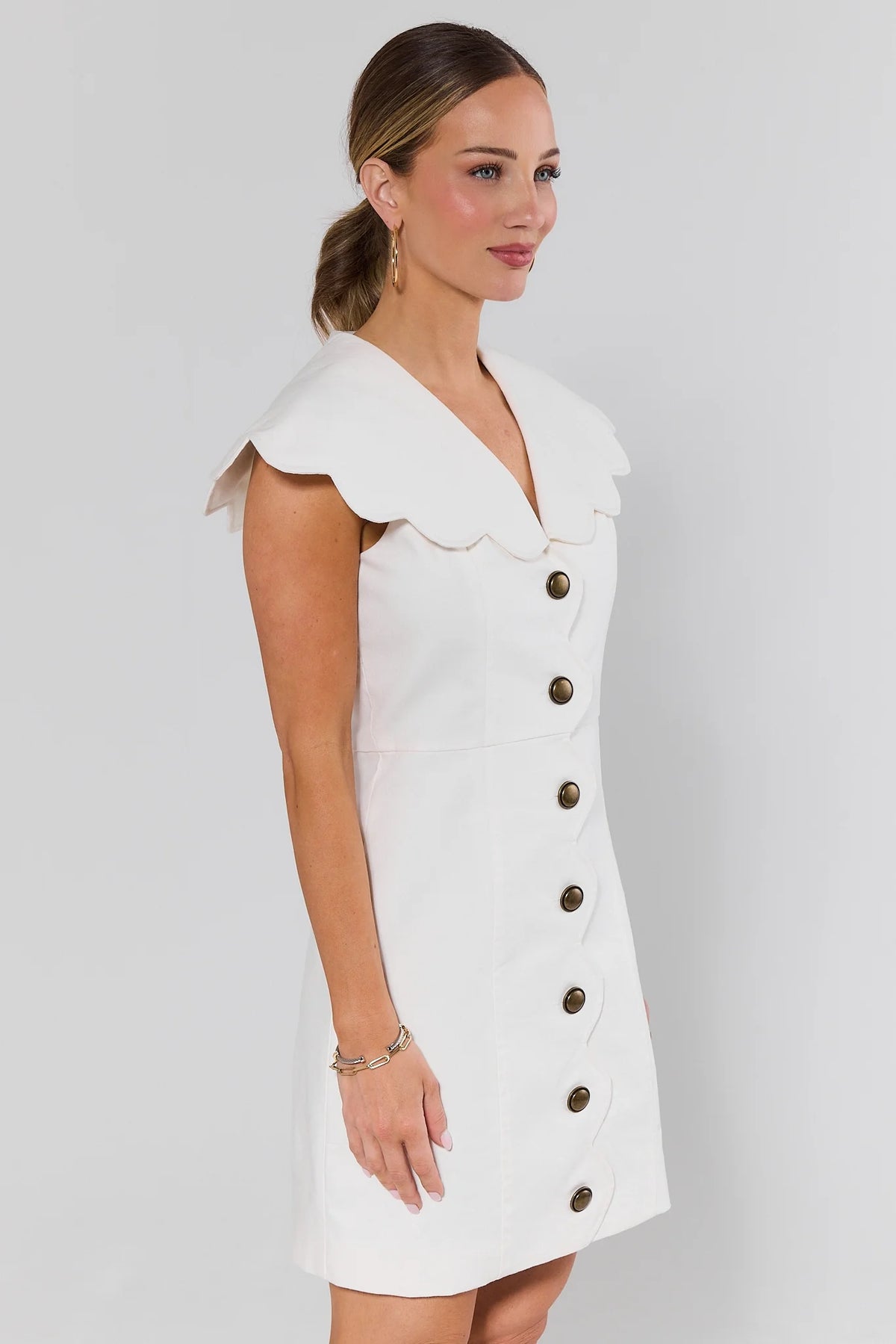 Kaia White Scalloped Collar Short Dress, side profile showing A-line silhouette and brass buttons | Avara